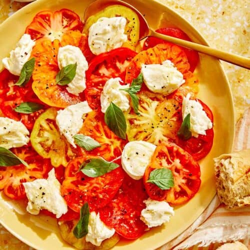 Caprese salad recipe on a platter with a gold spoon in it.