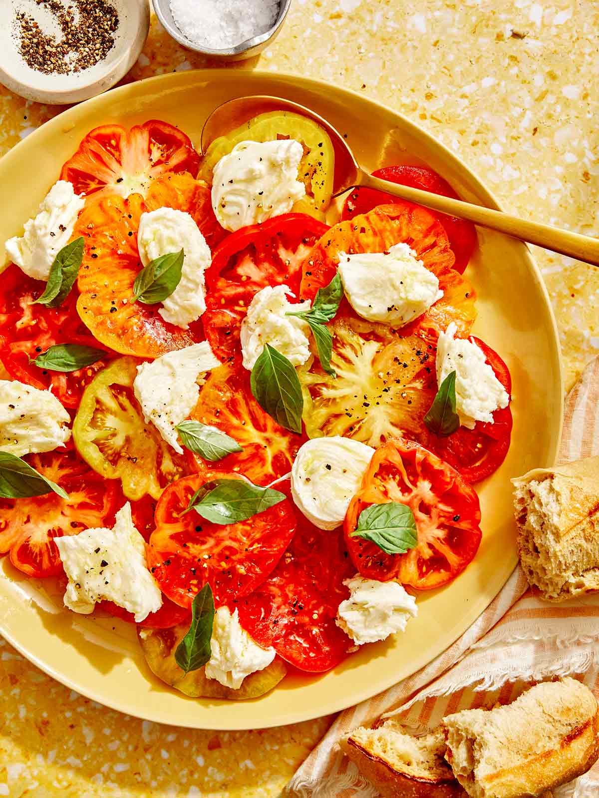 Caprese salad recipe on a platter with a gold spoon in it. 