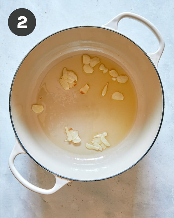 Garlic cooking in a pot with oil.