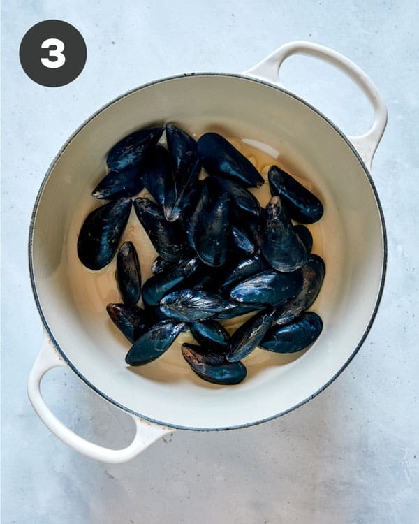 Mussels cooking in a pot with garlic and oil to make Frutti Di Mare.