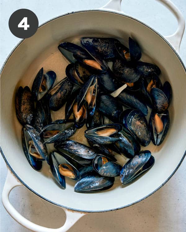 Cooked mussels in a pot with oil and garlic.