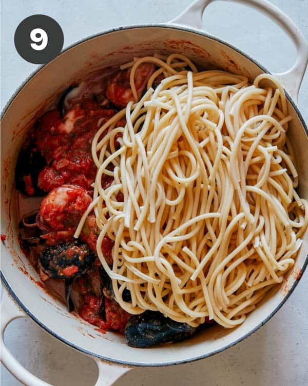 Frutti di mare with pasta being added to the pot.