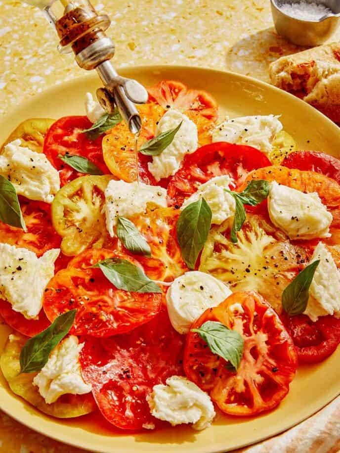 Caprese salad with olive oil being drizzled onto it.