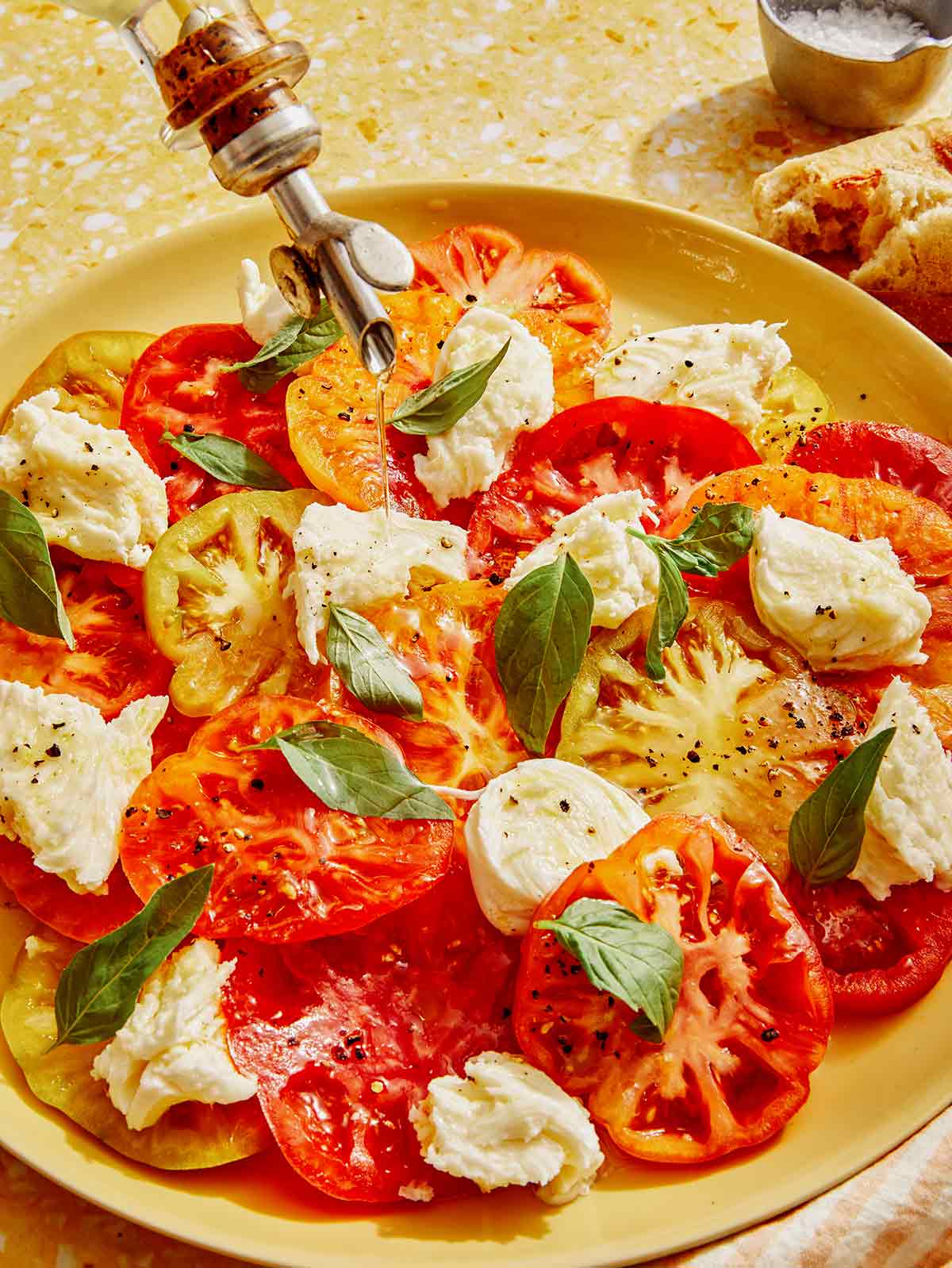 Caprese salad with olive oil being drizzled onto it. 