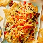 Taco dip on a platter with chips and beer on the side.