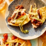 Taco dip with chips dipped into it on a plate.