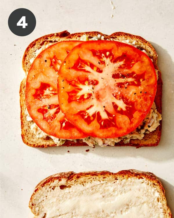 Tomatoes on top of tuna salad on bread. 