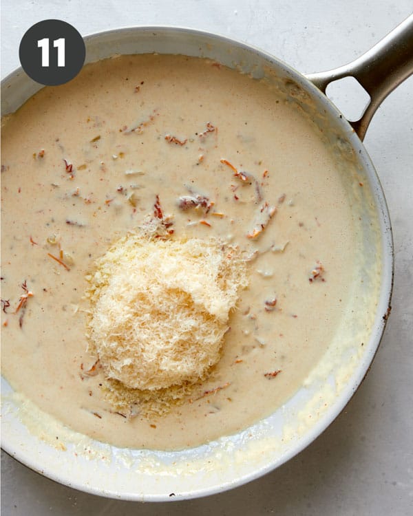Adding parmesan to sauce in a skillet for tuscan chicken.