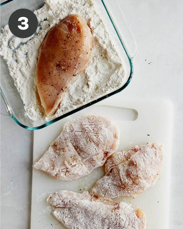Chicken breasts being dredged in flour to make tuscan chicken. 