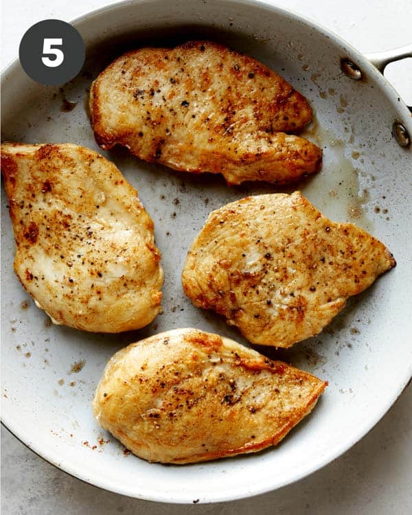 Chicken seared in a skillet with butter for tuscan chicken.