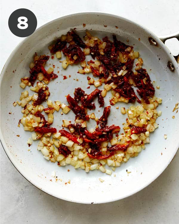 Onions and sun dried tomatoes cooking in a skillet to make Tuscan Chicken.