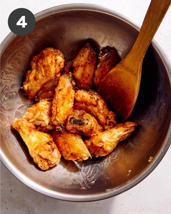 Chicken wings in a bowl with butter tossed into them. 