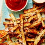 Air fryer french fries on a platter with ketchup and mayo.