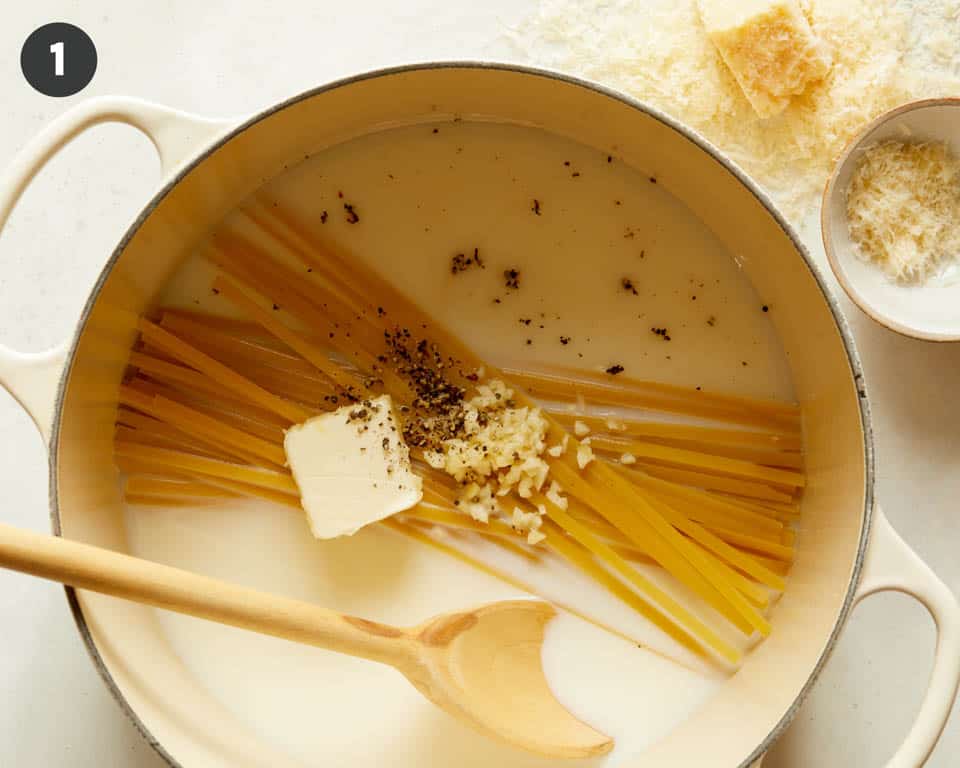 One pot fettuccine alfredo in pot with a wooden spoon.