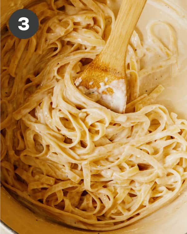 Close up of fettuccine alfredo with a wooden spoon.