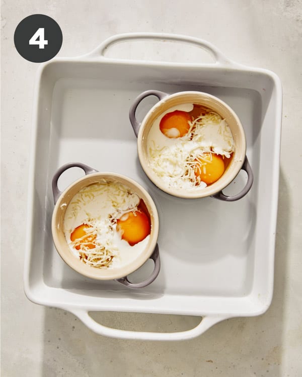 Eggs in cocotte in a baking dish surrounded by water.
