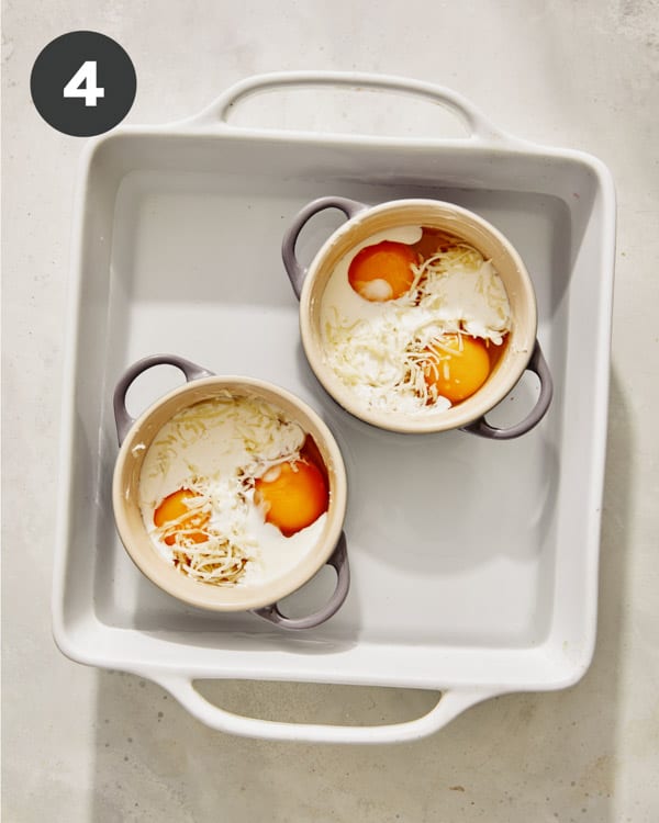 Eggs in cocotte in a baking dish surrounded by water. 