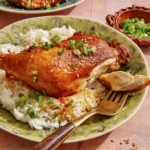 Garlic and ginger braised chicken with a piece of it on a fork.