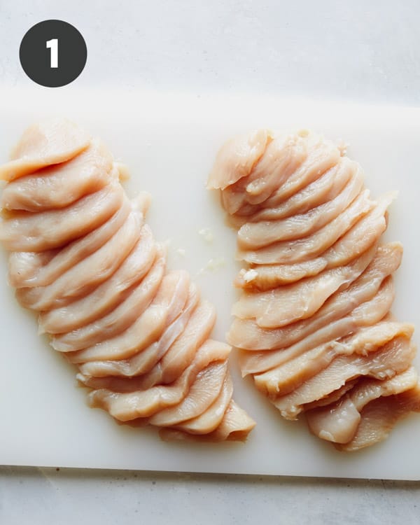Chicken breast cut up on a cutting board.