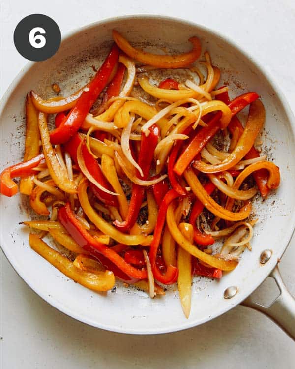 Bell peppers cooking in a skillet.