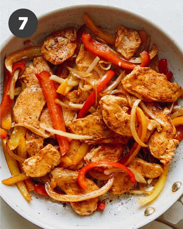 Chicken fajitas in skillet cooking.