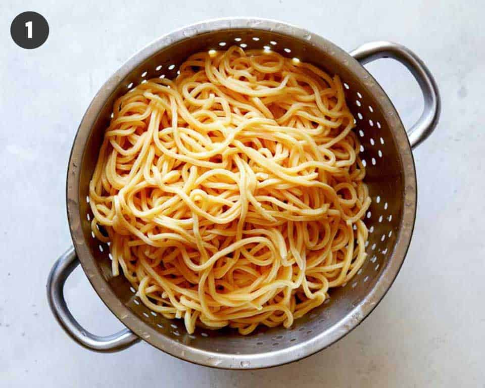 Cooked Chinese style egg noodles sitting in a colander.