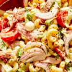 Grinder pasta salad up close with a spoon in the bowl.