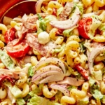 Grinder pasta salad up close with a spoon in the bowl.