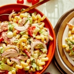 Grinder pasta salad being served onto plates.