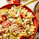 Grinder pasta salad in a bowl with a spoon in it.