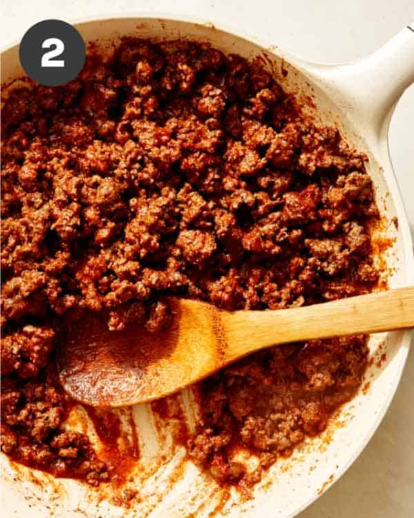 Ground beef cooking in a skillet with spices to make taco dip.