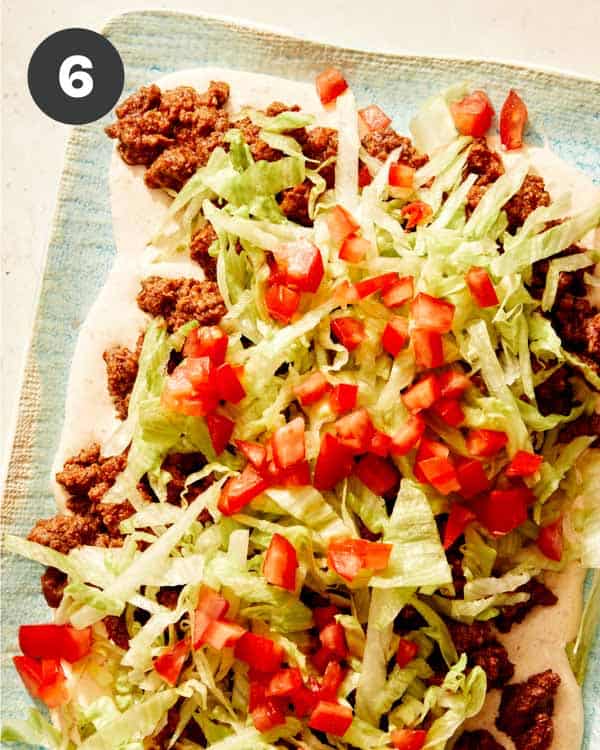 Taco dip with toppings being added to the top.