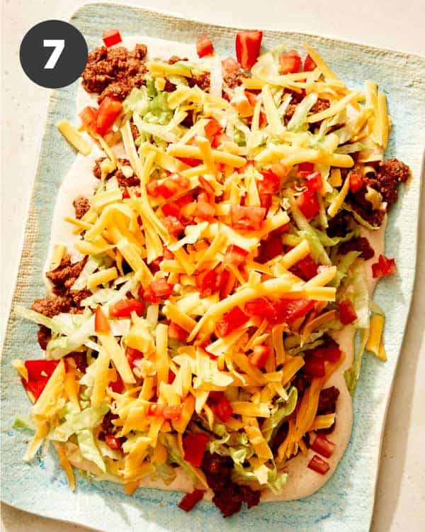 Taco dip with cheese and tomatoes added to the top.