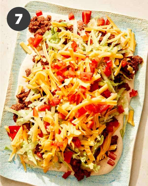 Taco dip with cheese and tomatoes added to the top. 