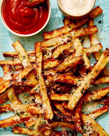 Air fryer french fries on a platter with ketchup and mayo.
