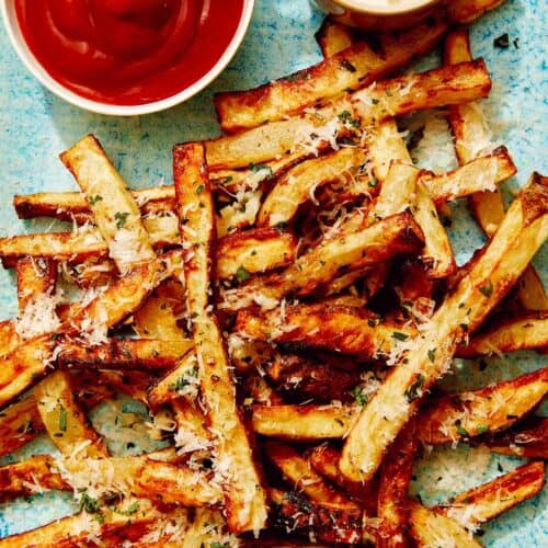 Air fryer french fries on a platter with ketchup and mayo.