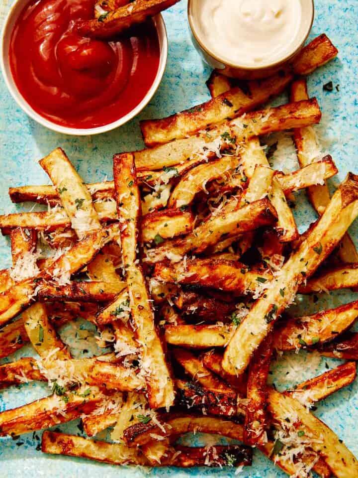 Air fryer french fries on a platter with ketchup and mayo.