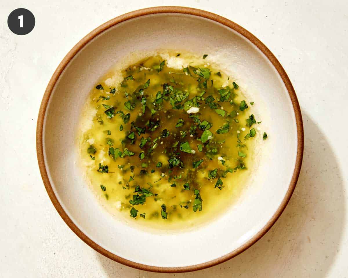 Oil, garlic, and herbs, with melted butter in a bowl to drizzle on air fryer french fries.