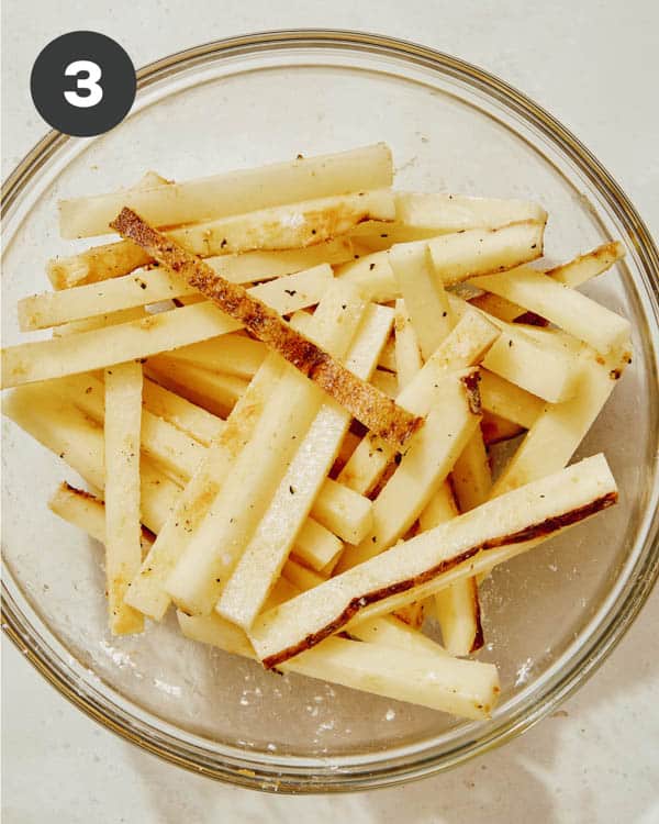 French fries seasoned in a bowl with salt and pepper. 