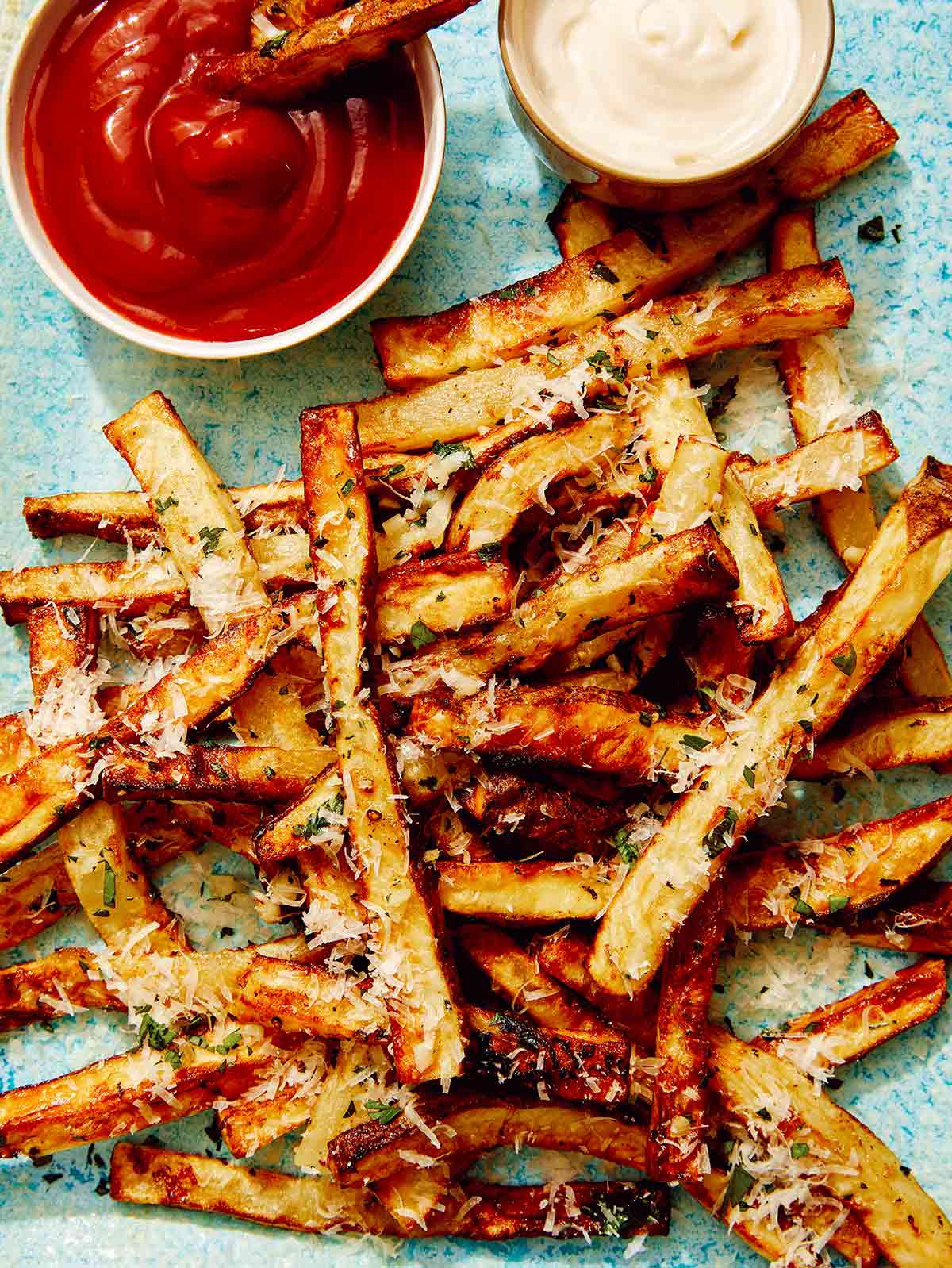 Air fryer french fries on a platter with ketchup and mayo. 