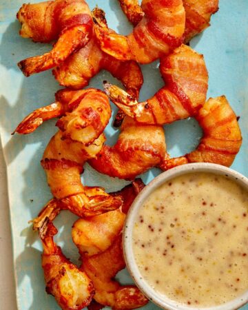 Air fryer bacon wrapped shrimp on a platter with honey mustard.