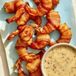 Air fryer bacon wrapped shrimp on a platter with honey mustard.