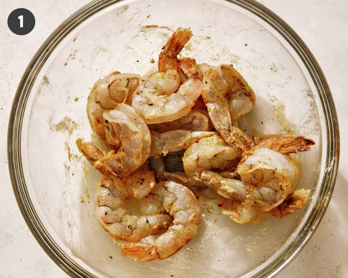 Shrimp seasoned and mixed with oil in a glass bowl. 