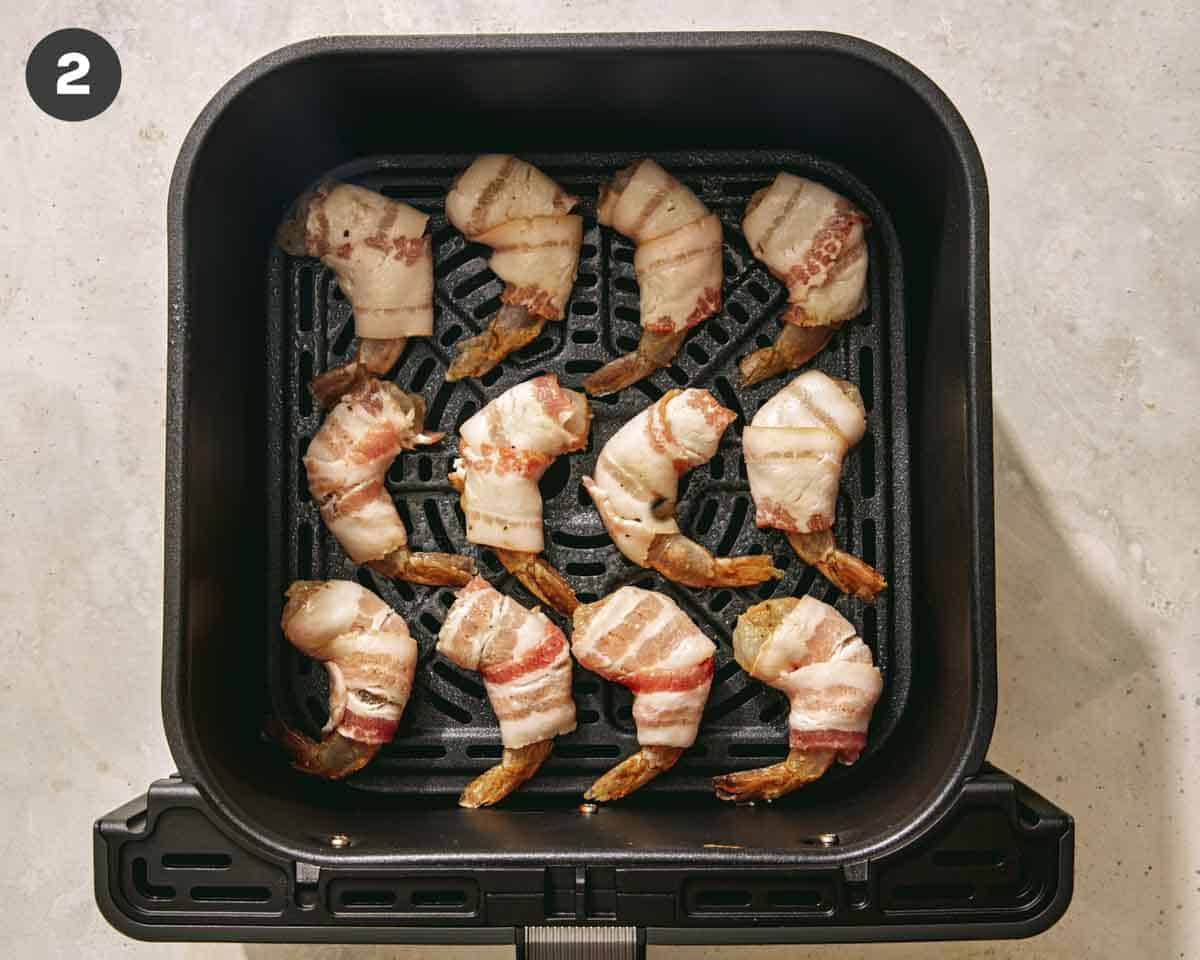 Shrimp wrapped in bacon and in an air fryer ready to be cooked. 
