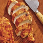 Air fryer chicken breasts on a cutting board.