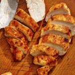 Air fryer chicken breast on a cutting board with a knife.