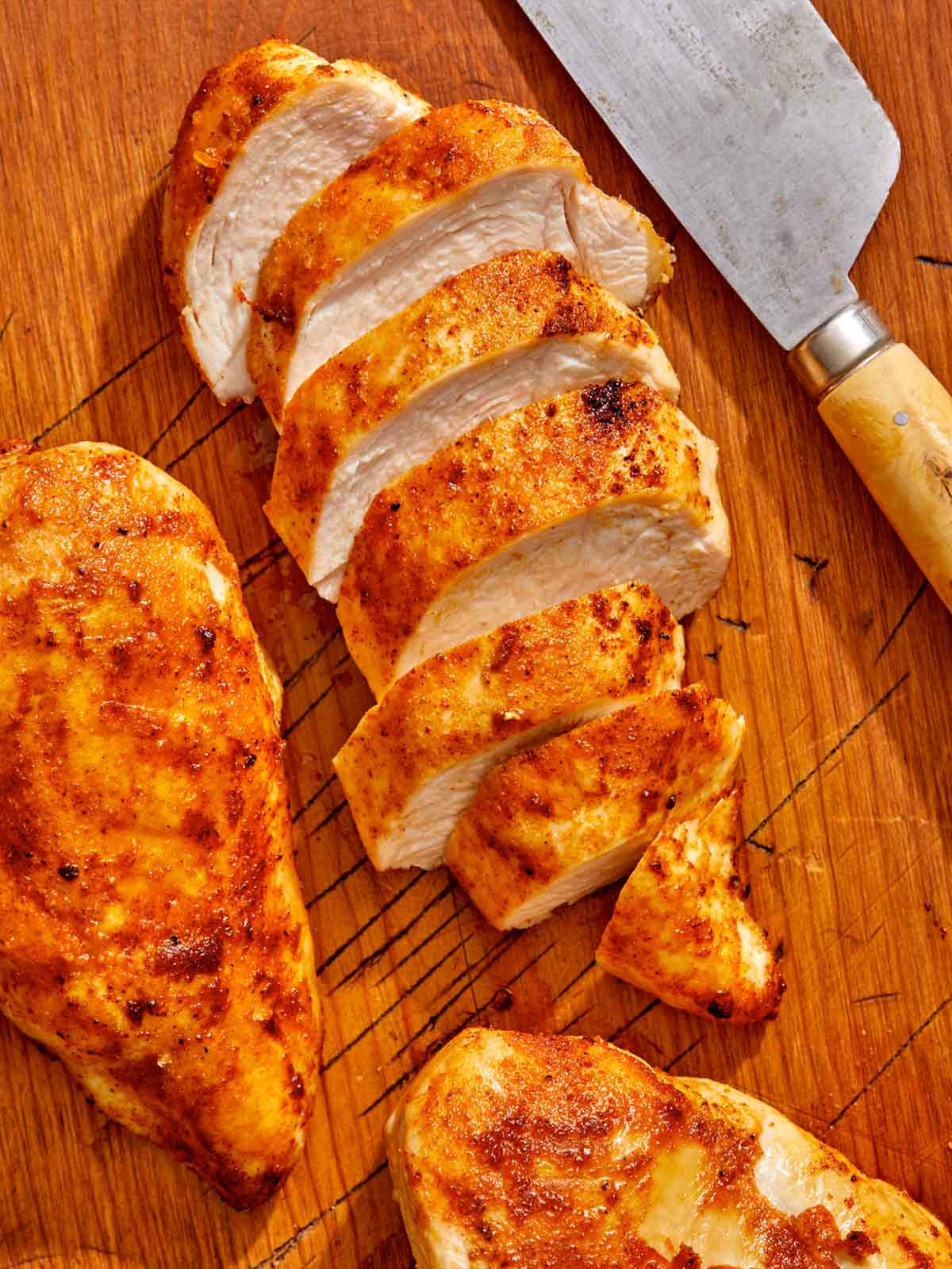 Air fryer chicken breast on a cutting board with a knife. 