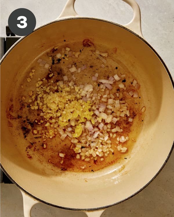 Garlic, shallots, and ginger being cooked in a pot. 