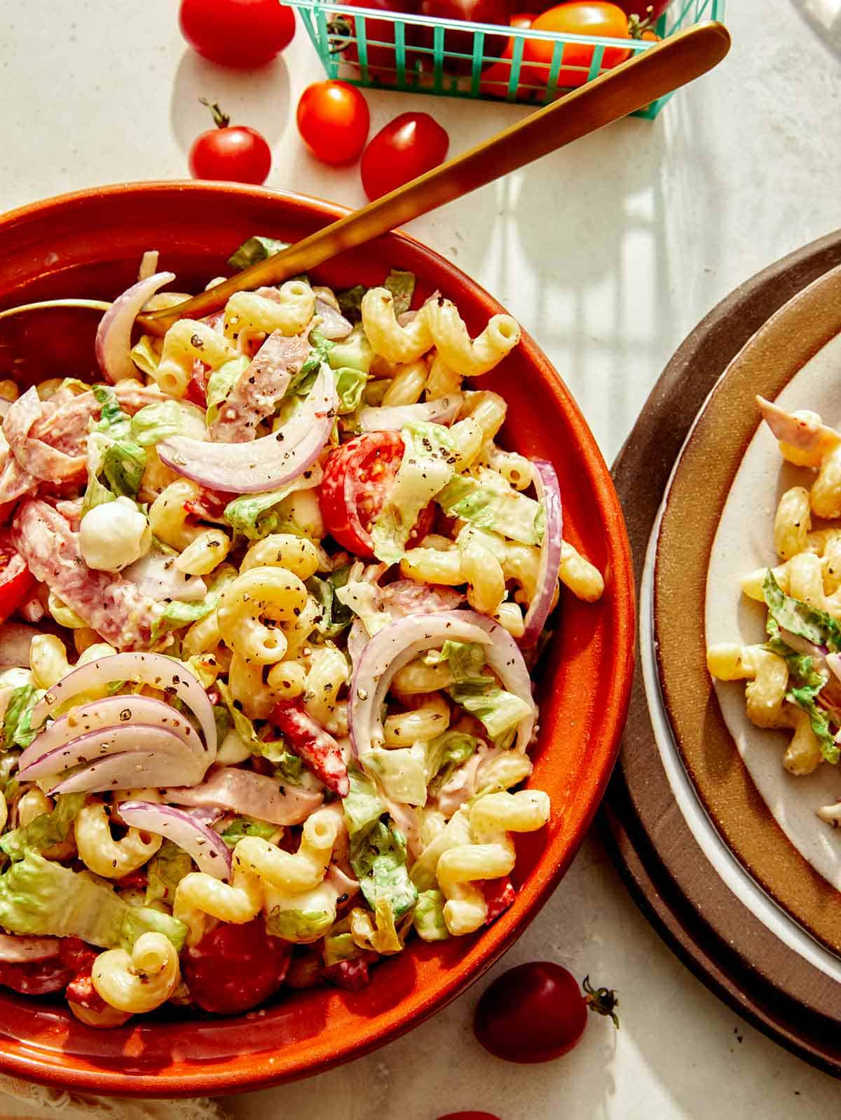 Grinder pasta salad being served onto plates.