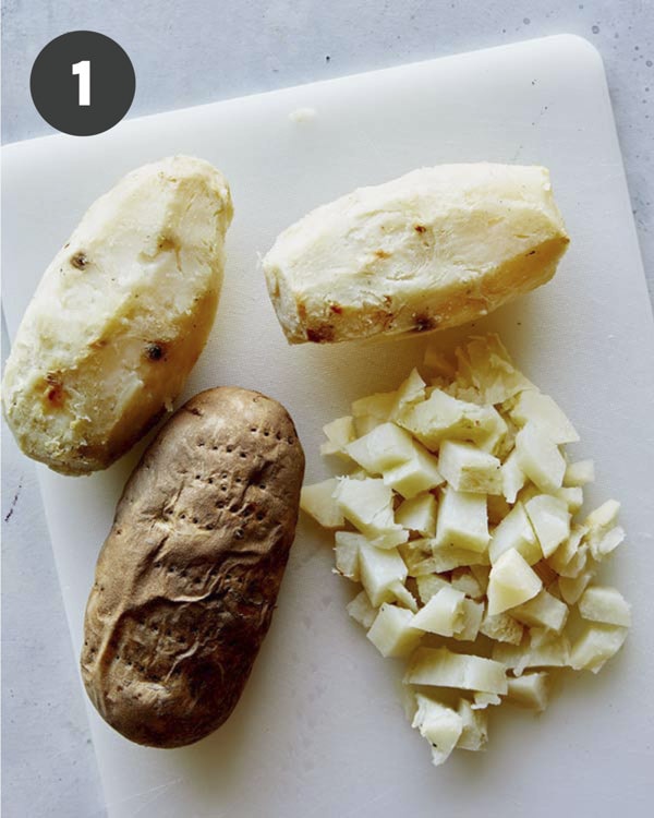 Baked potatoes peeled and diced on a cutting board. 